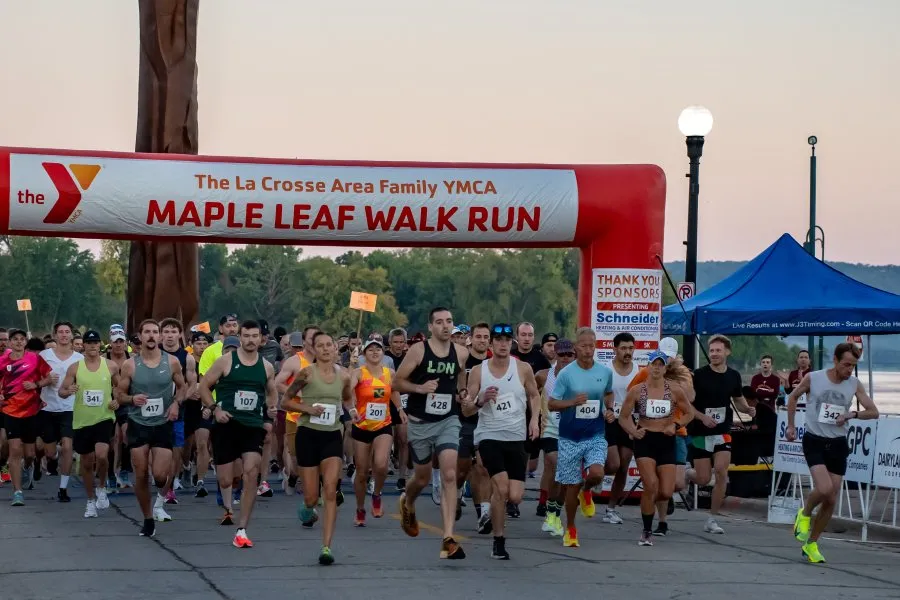 Runners starting the YMCA Maple Leaf Walk Run under a large inflatable arch.